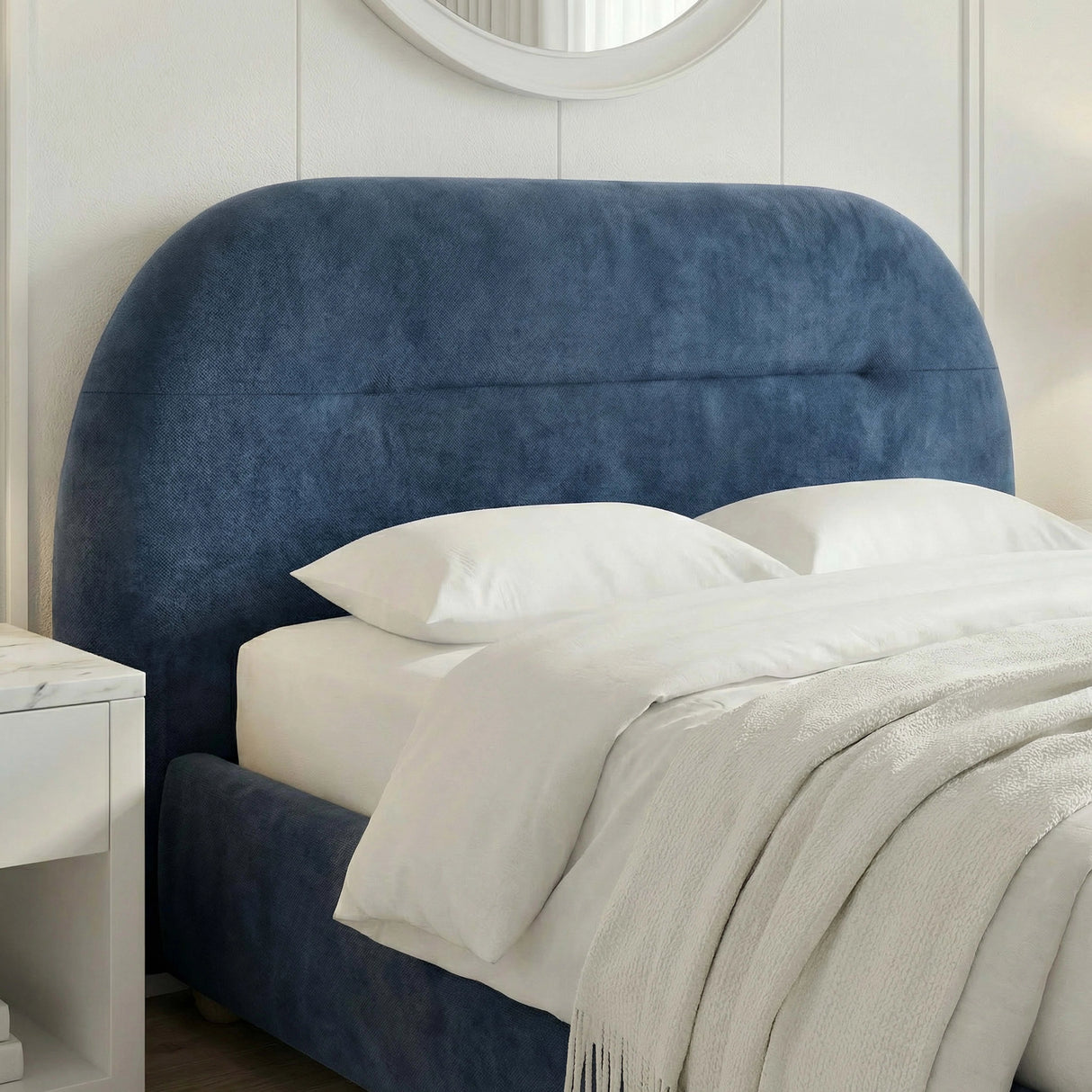 Detailed view of the headboard of the king size blue upholstered bed with light linens in stylish room