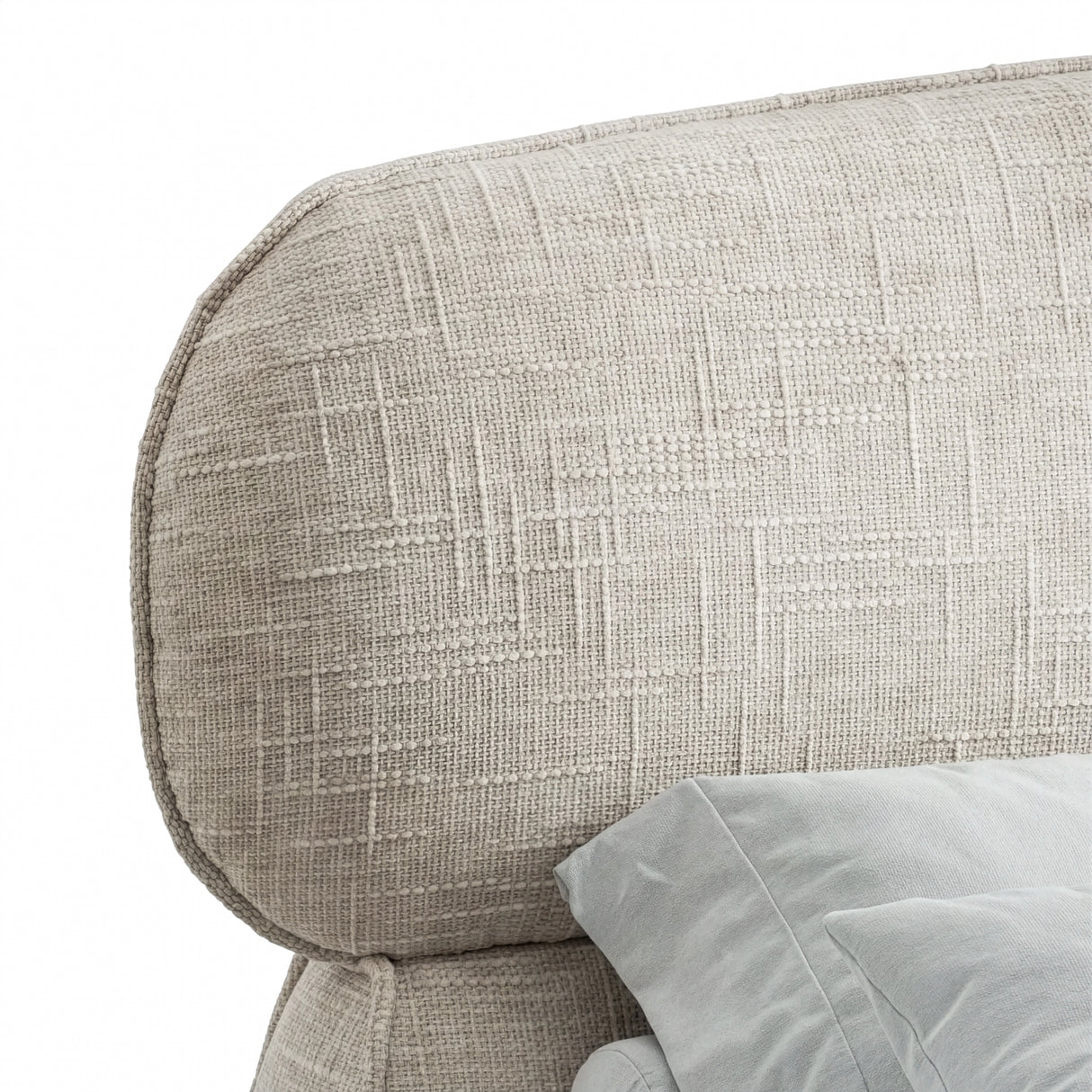 Close view of camel fabric padded headrest with rounded edges and fine texture, with a light bedding