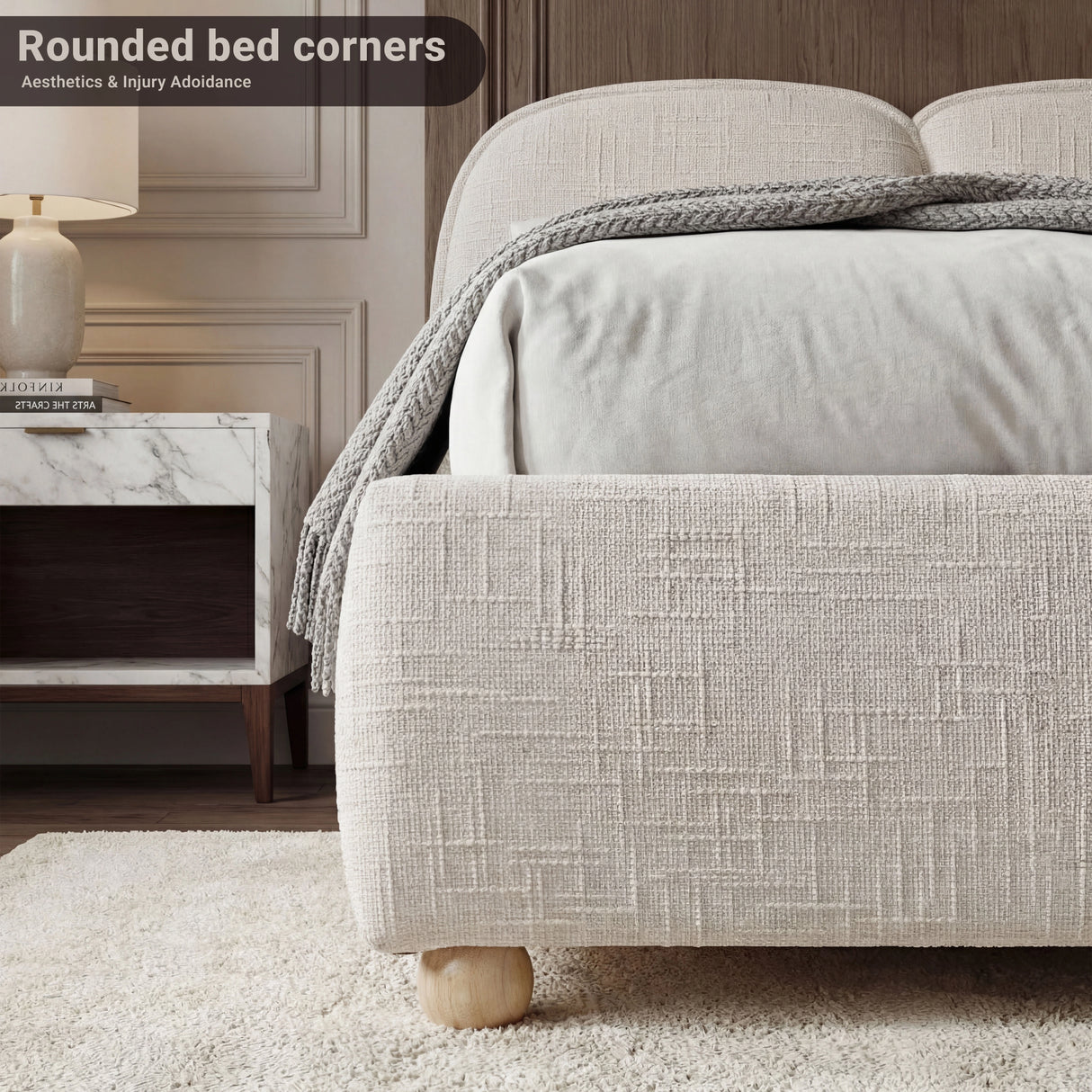 Close view of a beige fabric-wrapped bed base end with rounded edges, textured upholstery, and a low-profile stance on the floor