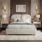 Front view of a king-size grey beige upholstered bed frame with curved headboard design, and warm bedside lighting