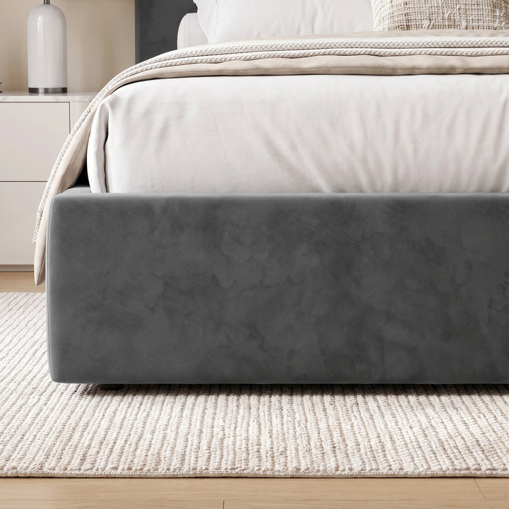 [King | Grey] A dark gray upholstered bed frame shown in a styled bedroom setting, with white bedding, a beige throw blanket, a woven rug, and a light wood floor.