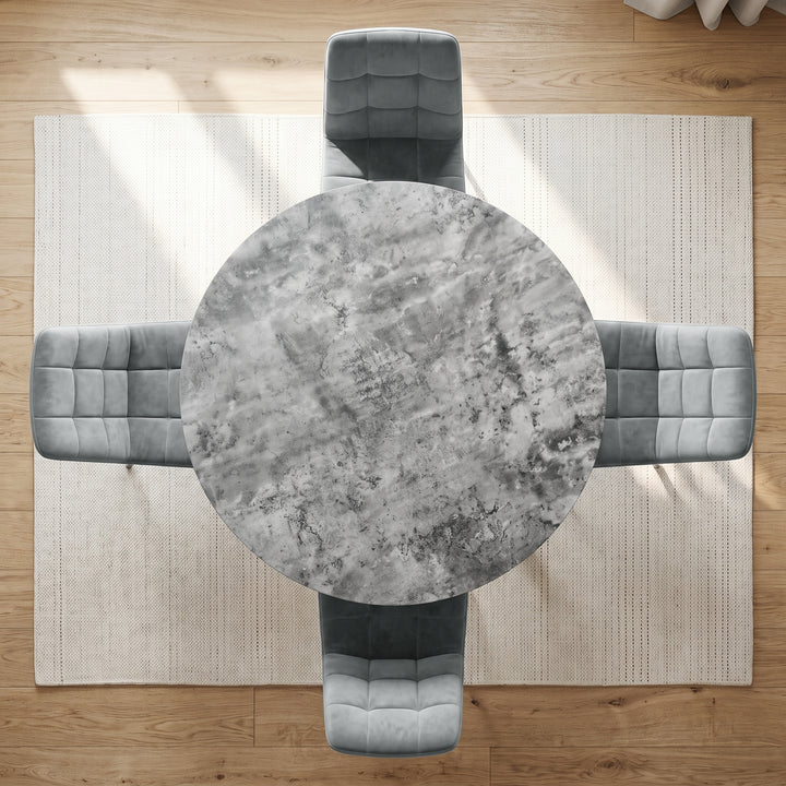 [Light Grey]  Overhead view of a round dining table with a gray marbled top, surrounded by four gray upholstered chairs on a light beige rug over a wood floor.