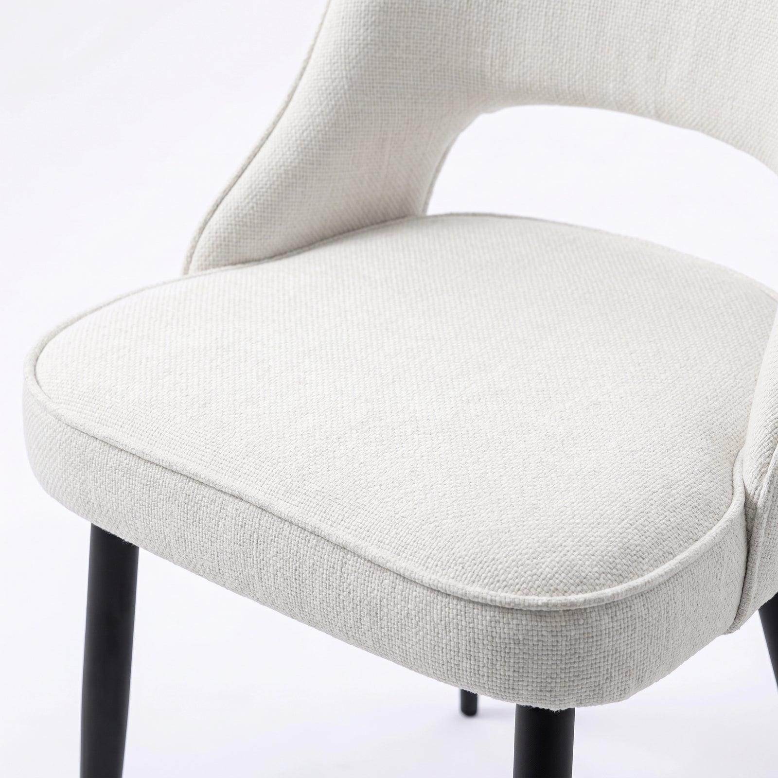 [Cream | Clear] Close-up of Kyvon 4-seater cream upholstered fabric comfy curve chair seat with black metal legs