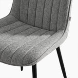 [Vertical Grey | Clear] Close-up of Kyvon grey upholstered fabric channeled stitched chair seat with black metal legs