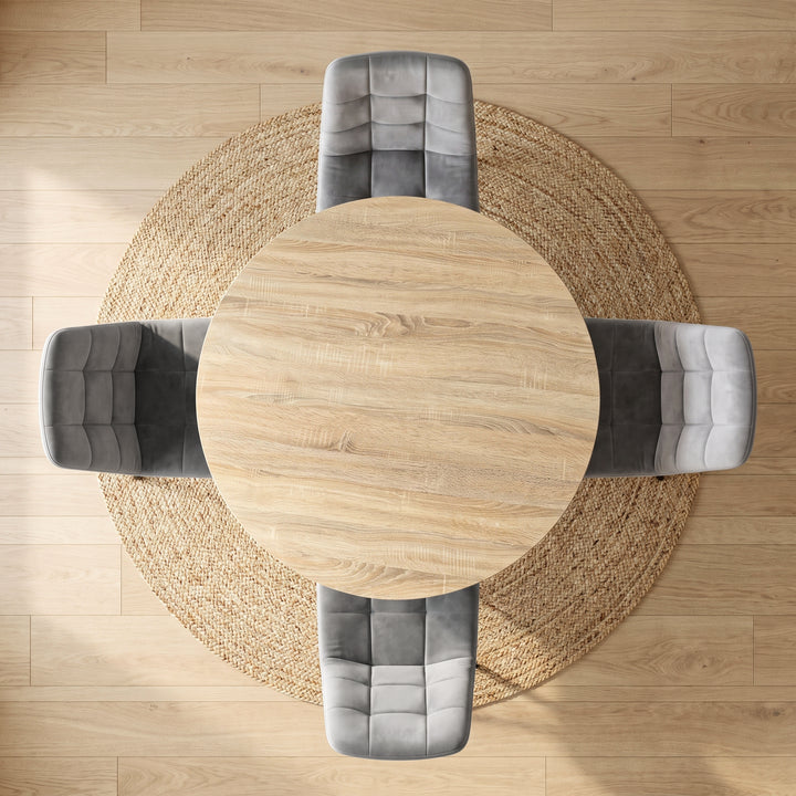 [Light Grey | Sonoma Oak] Overhead view of a round light oak dining table surrounded by four gray tufted velvet chairs on a round natural jute rug over a light wood floor.
