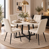 [Cream] A round white marble dining table with black metal legs, surrounded by four tufted off-white upholstered dining chairs on a round beige rug in a modern dining room setting.