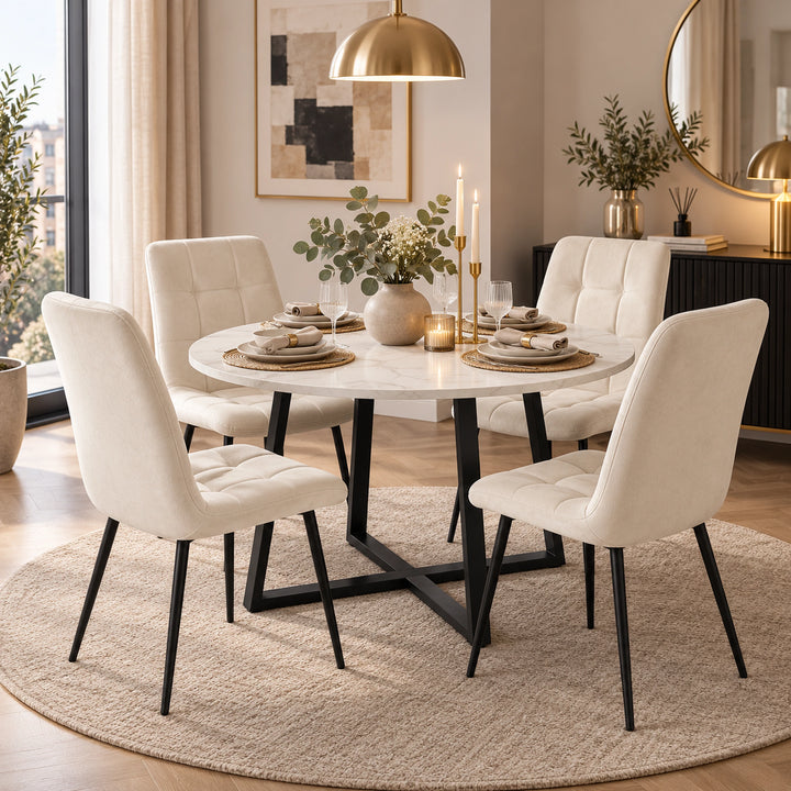 [Cream] A round white marble dining table with black metal legs, surrounded by four tufted off-white upholstered dining chairs on a round beige rug in a modern dining room setting.