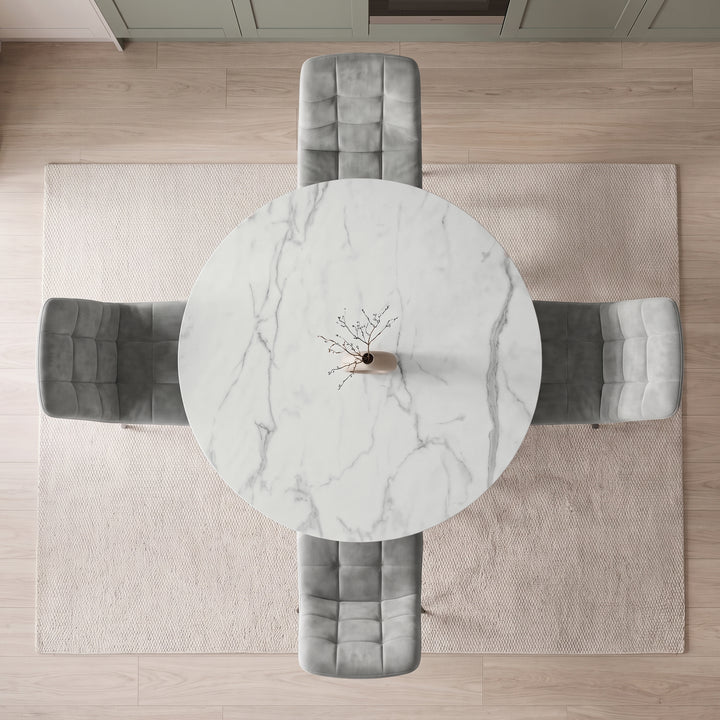 [Light Grey | White Marble] Overhead view of a round white marble dining table with gray tufted velvet chairs, placed on a light beige rug over a light wood floor.