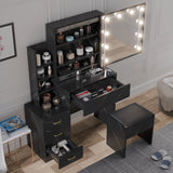 Black vanity table with mirror and lights, surrounded by various items, in a room setting.