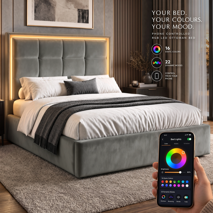 [Grey | Double] bedroom scene shows a light grey upholstered bed with a glowing LED headboard and a hand holding a smartphone that displays the app controlling the bed lights.