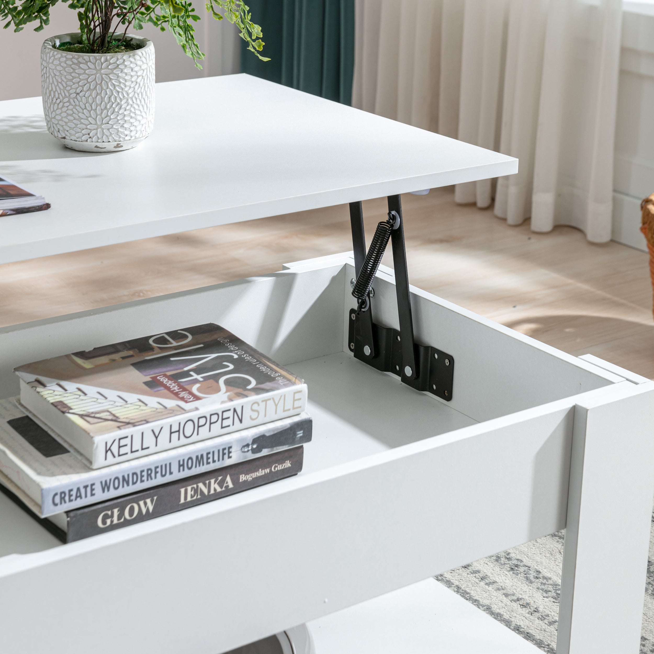 Close up of white lift-top coffee table with spring mechanism and books stacked in lower compartment