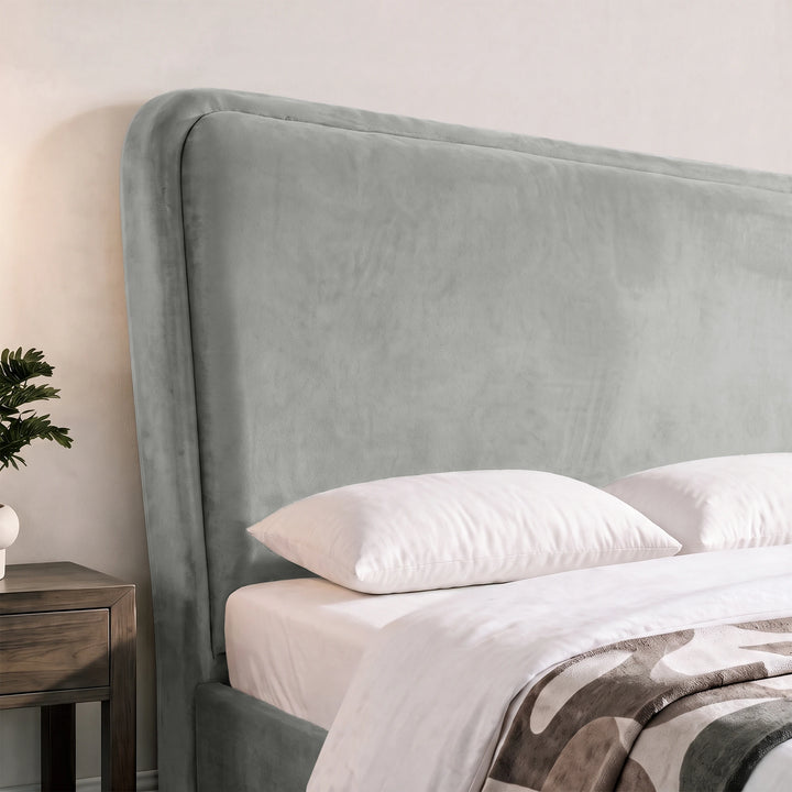 [Double | Light Grey] Close-up of tall padded headboard with rounded border, velvet texture and pillows against the frame