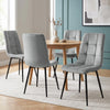 [Light Grey] Velvet dining chairs around a round table, showing tufted fronts and smooth curved backs from behind.