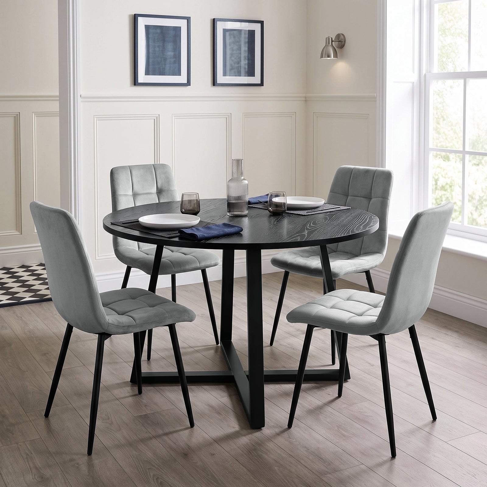 [Light Grey] Velvet dining chairs around a round black table, with curved backs, tufted seats and black legs.