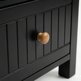 [Black] Detail of the Linra bedside table painted drawer with vertical groove lines and a natural wood pull knob