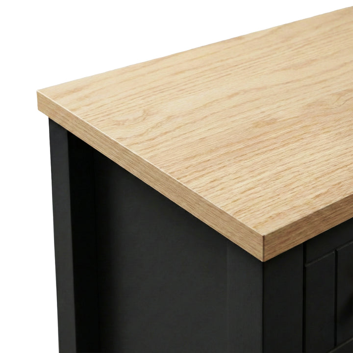 [Black] Top-corner close-up of the Linra bedside table showing the oak veneer surface meeting the black painted side