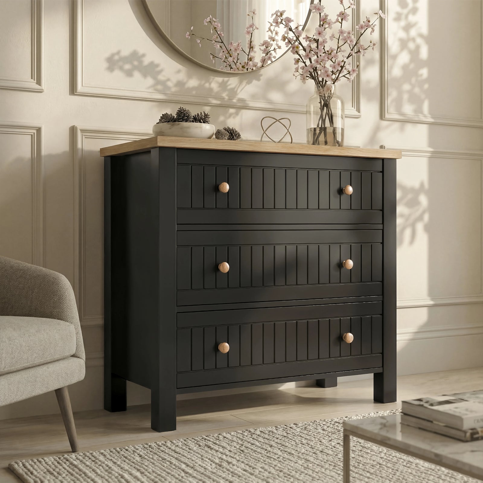 [Black] Linra chest of drawers in black photographed from side, oak top with vase of stems beside chair