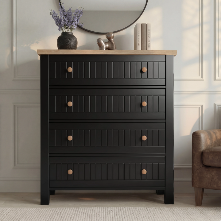 [Black] Linra 4-drawer chest front view in a styled room with round mirror and decorative objects on oak top