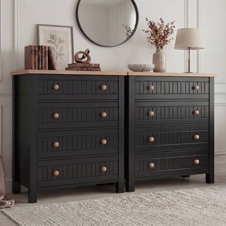 [Black] Linra 4-drawer chest pair view in a styled bedroom with round mirror, vase and lamp on oak veneer top
