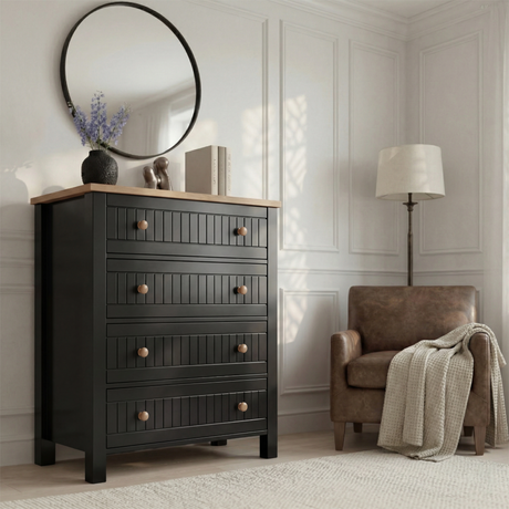 [Black] Linra 4-drawer chest in a wider bedroom lifestyle setting with armchair and accessories on oak veneer top
