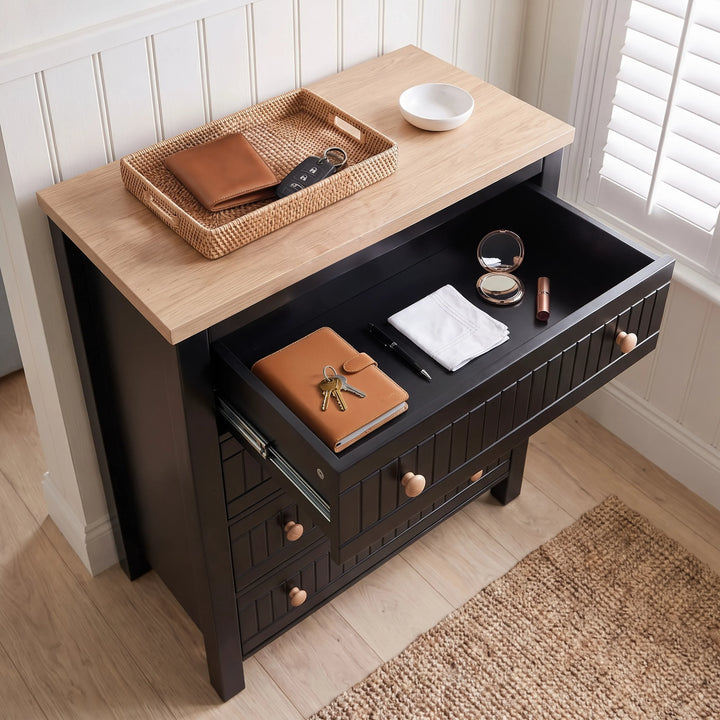 [Black] Linra 4-drawer chest with top drawer open showing interior depth and accessories arranged on oak veneer top