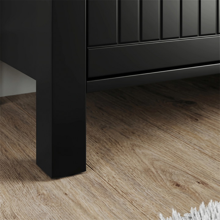 [Black] Detail of Linra 135cm sideboard base, square black leg under beaded door panel on oak-effect flooring