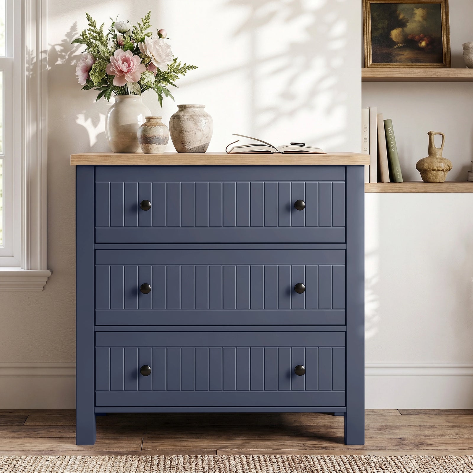 [Blue] Linra chest of drawers in panelled hallway beneath round wood-framed mirror with hydrangeas