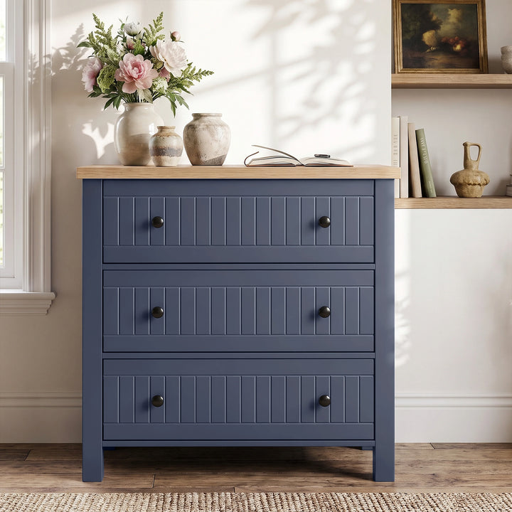 [Blue] Linra chest of drawers in panelled hallway beneath round wood-framed mirror with hydrangeas
