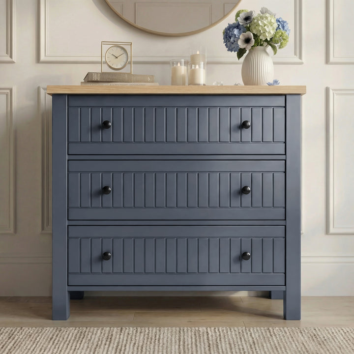 [Blue] Linra chest of drawers in panelled hallway beneath round wood-framed mirror with hydrangeas