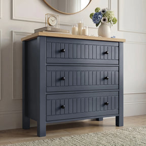 [Blue] Linra chest of drawers front view styled with clock, books and floral vase on oak veneer top