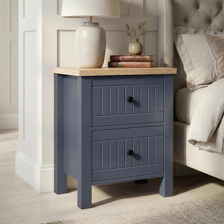 [Blue] Linra 2-drawer bedside table side view on plain background showing lamp, books, frame depth and oak top
