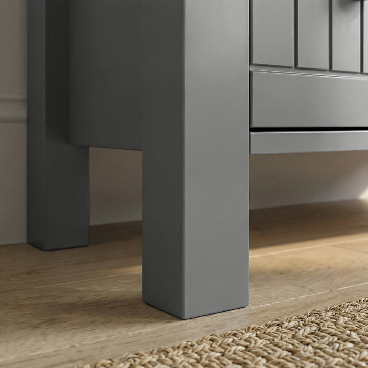 [Grey] Linra 3-drawer chest angled close-up of painted frame leg base corner showing beaded panel door detail