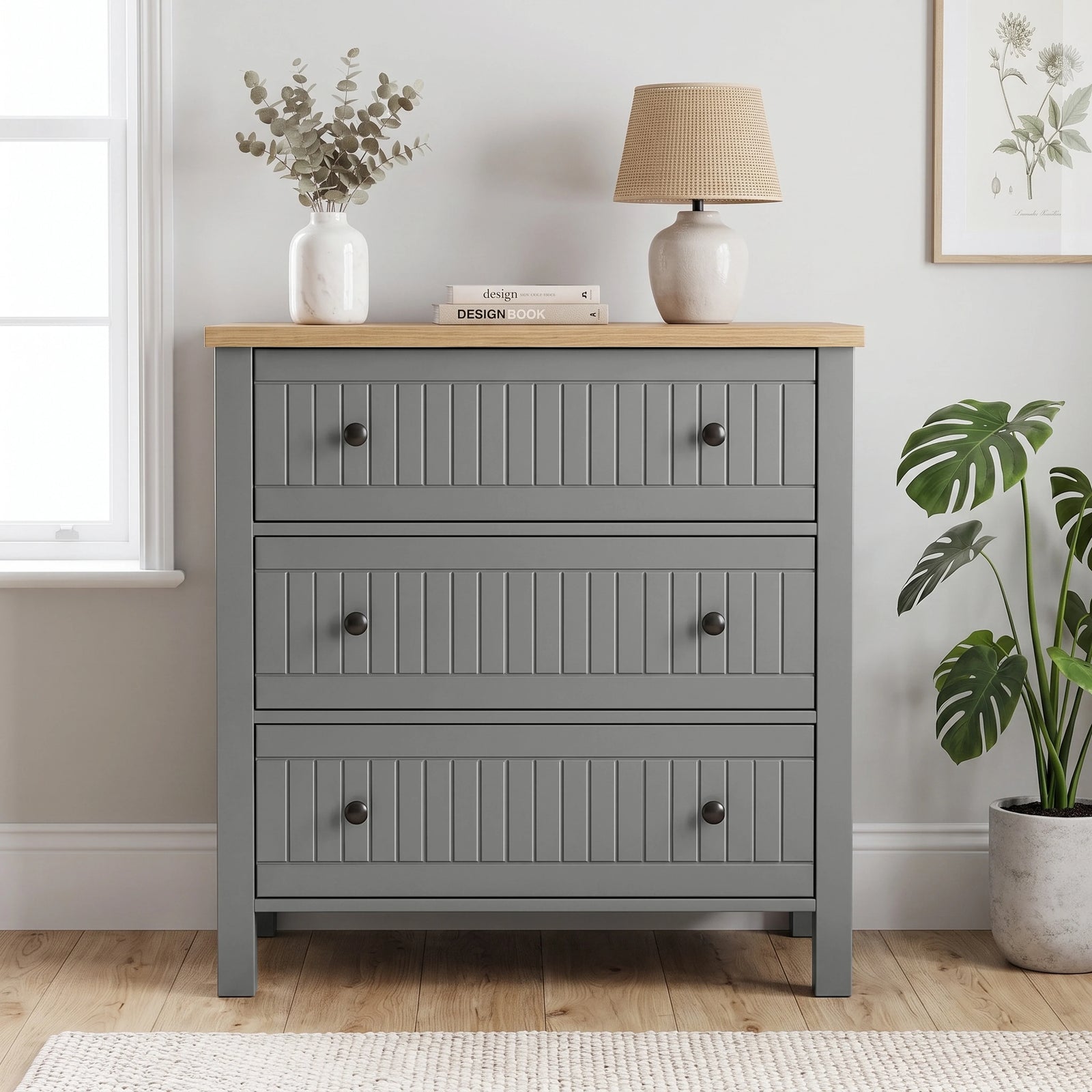 [Grey] Linra 3-drawer chest front view in a styled room with round mirror and decorative objects on oak veneer top