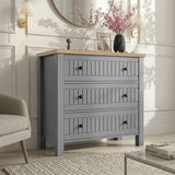 [Grey] Linra 3-drawer chest in a wider bedroom lifestyle setting with armchair and accessories on oak veneer top