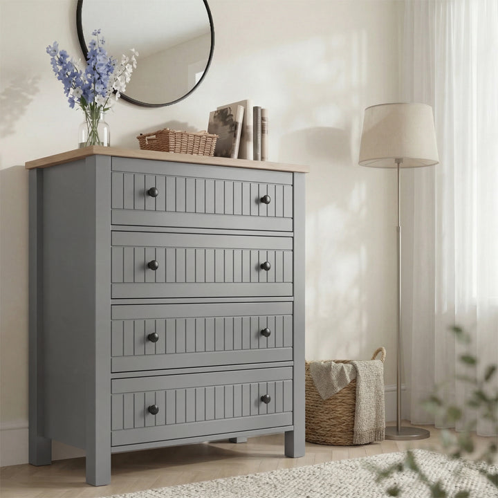 Linra 4-drawer chest in a styled bedroom with floor lamp on the right and round mirror above oak top