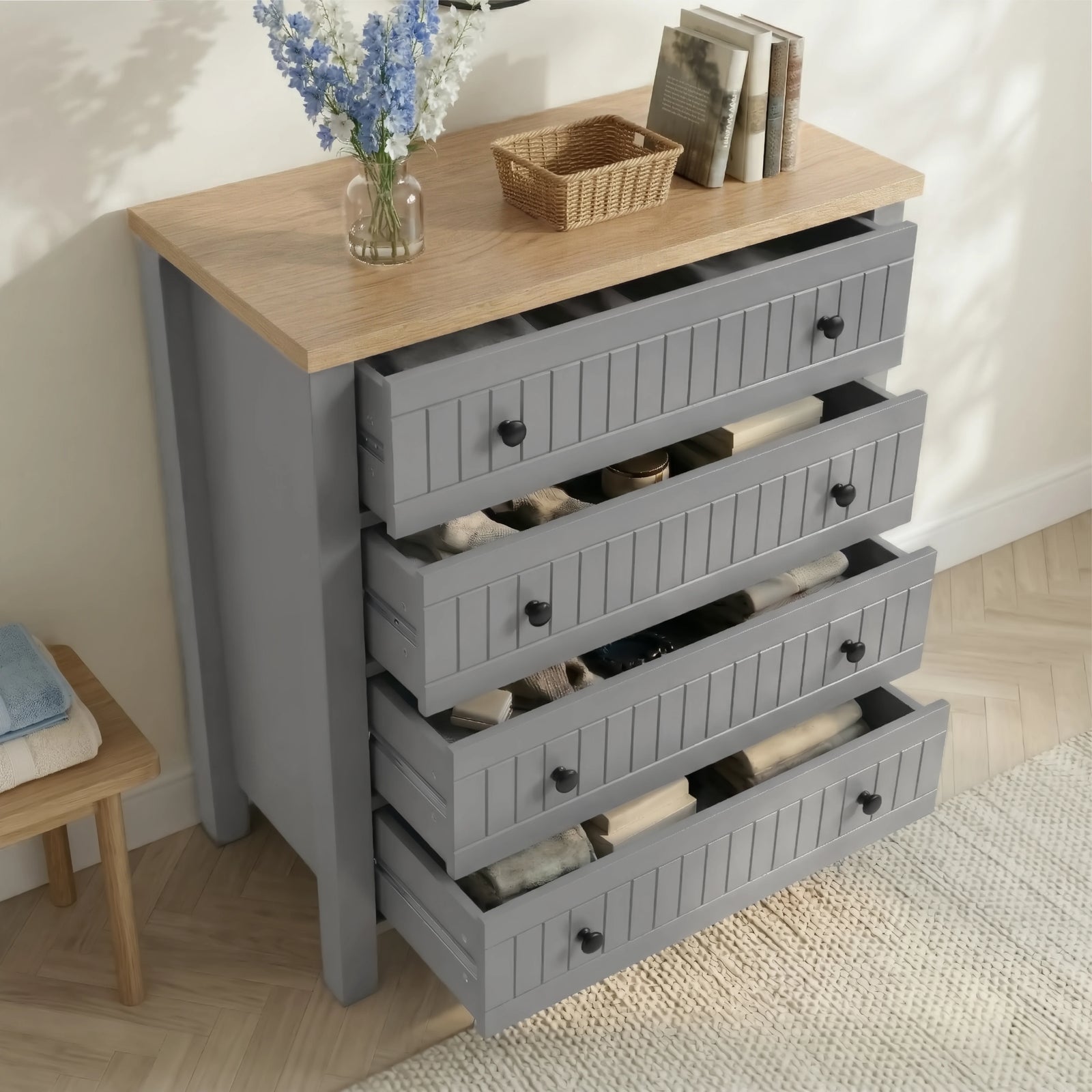 [Grey] Linra 4-drawer chest with drawers open in a styled room showing interior depth and accessories on oak top