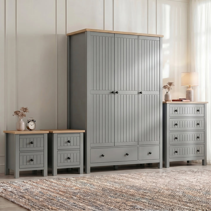 [Grey] Four piece Linra bedroom furniture set staged with woven rug, lamp and dried stems against panelled wall