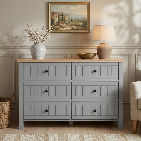 [Grey] Linra 6-drawer chest front view in a styled room with neutral wall, lamp and artwork on the wall above