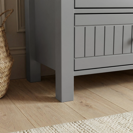 [Grey] Linra 6-drawer chest angled close-up of the side panel showing painted frame leg base and beaded door detail