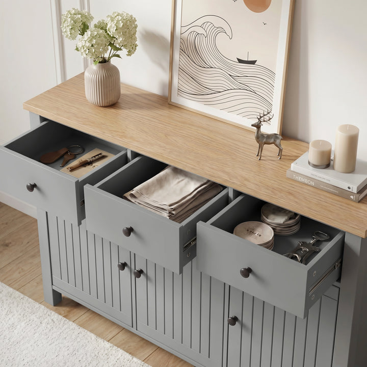 Linra grey sideboard with all three top drawers open revealing cutlery, folded napkins and plates inside