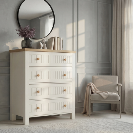 [White] Linra 4-drawer chest front view in a bedroom with round mirror, armchair and accessories on oak top