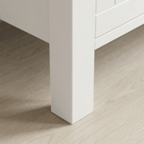 [White] Linra 4-drawer chest angled close-up of painted frame leg base corner showing beaded panel door detail