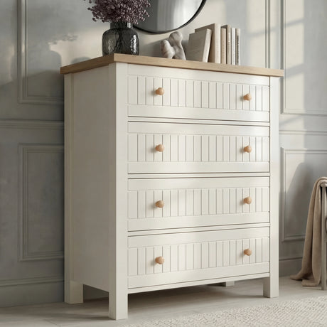 [White] Linra 4-drawer chest side angled view showing full height in a styled bedroom with mirror and books on top