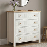 [White] Linra 4 drawer chest angled view with oak top styled with dried floral vase, sculptural ornament, and stacked books below round mirror