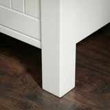 [White] Linra 5-drawer chest angled close-up of painted frame leg base corner showing beaded panel door detail