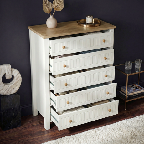 [White] Linra 5-drawer chest with drawers open in a styled room with dark wall and vase on oak veneer top