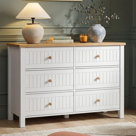 [White] Linra 6-drawer chest front view in a styled room with dark olive wall and decorative vases on oak top