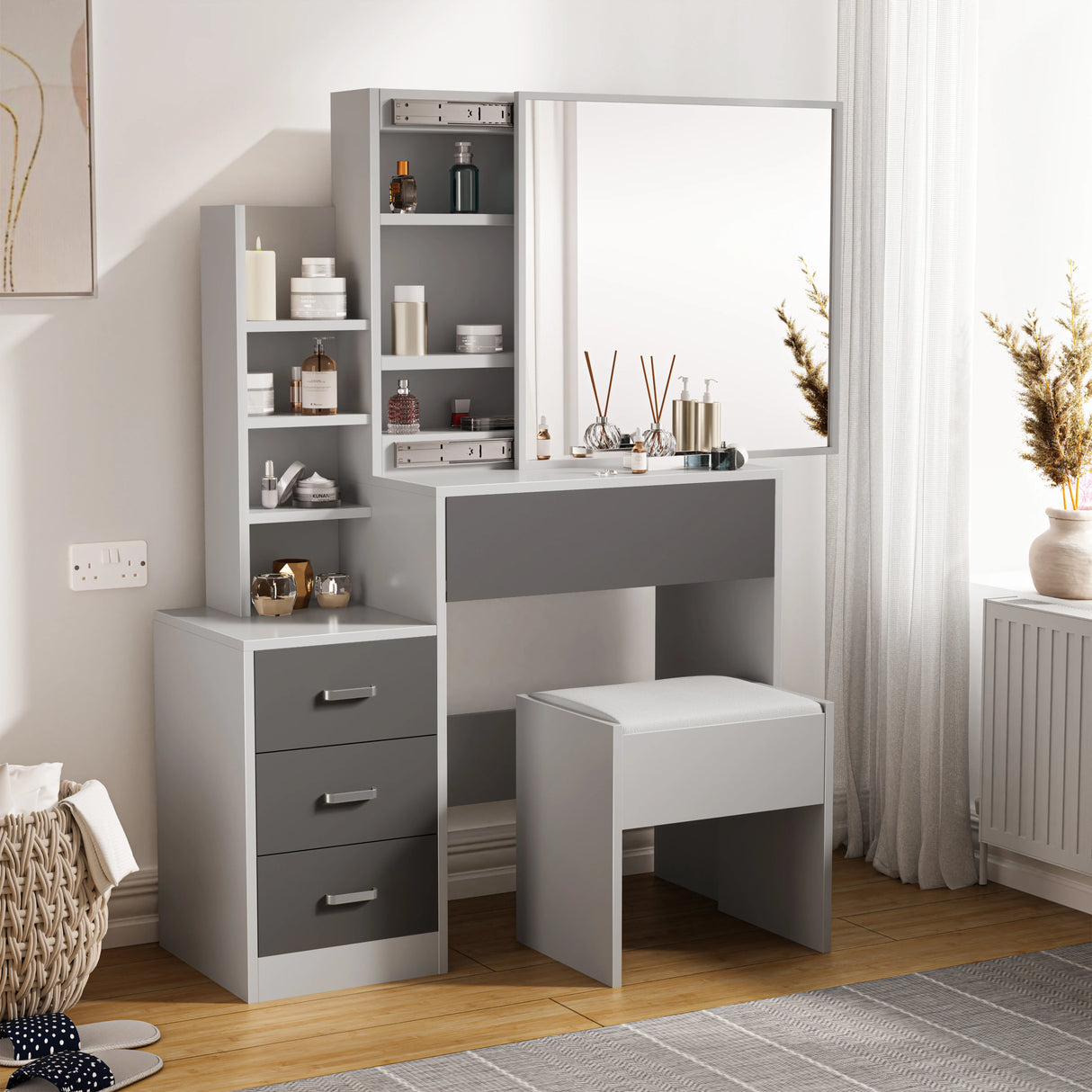Modern grey dressing table with storage, drawers, and large mirror. Includes cushioned stool and open shelving, ideal for bedroom makeup setup.