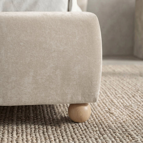 [Beige | Double] Round wooden ball foot at base corner sitting on woven jute rug with upholstered frame edge visible above