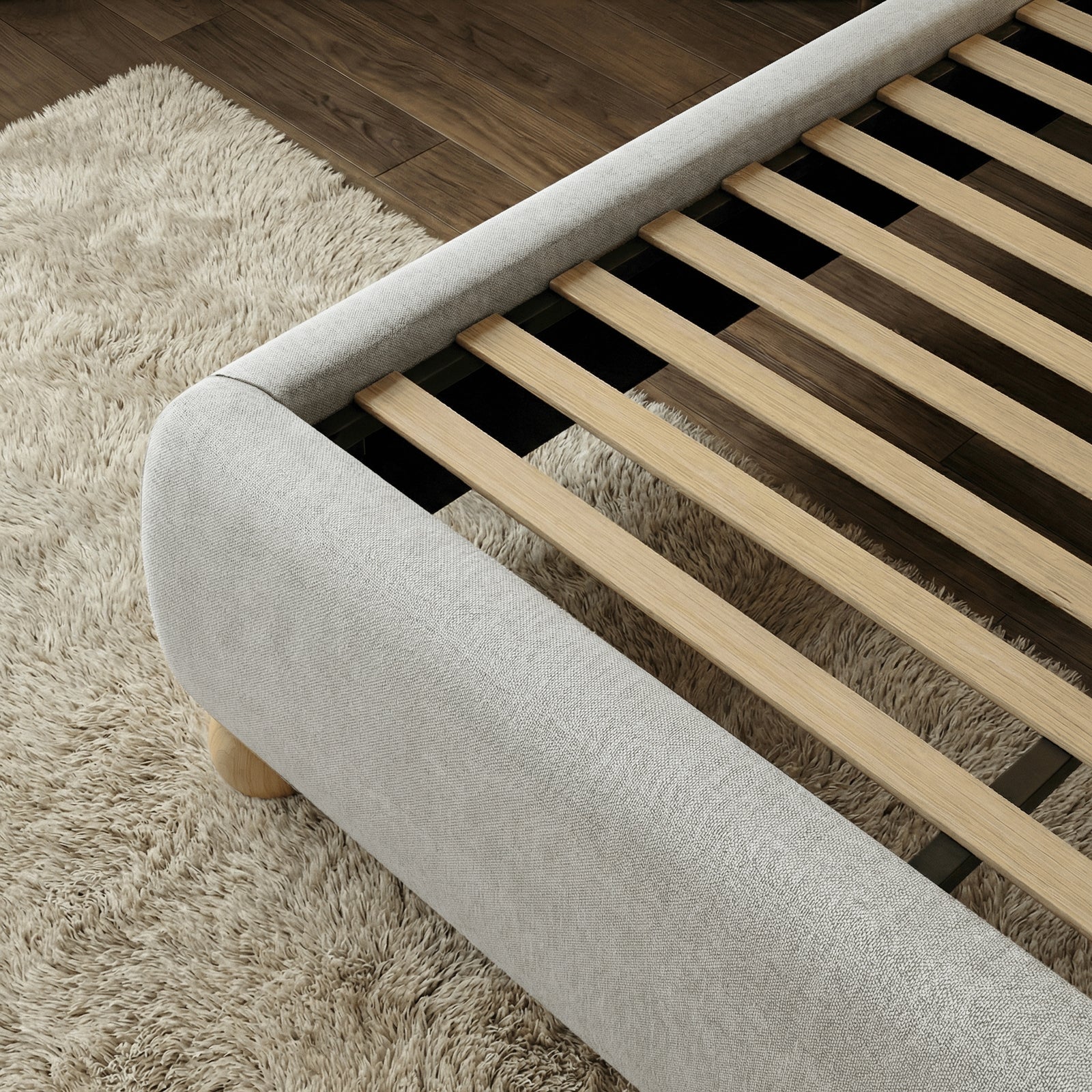 [Grey | King] Wooden slat base inside upholstered frame showing evenly spaced slats with padded curved rail on shag rug